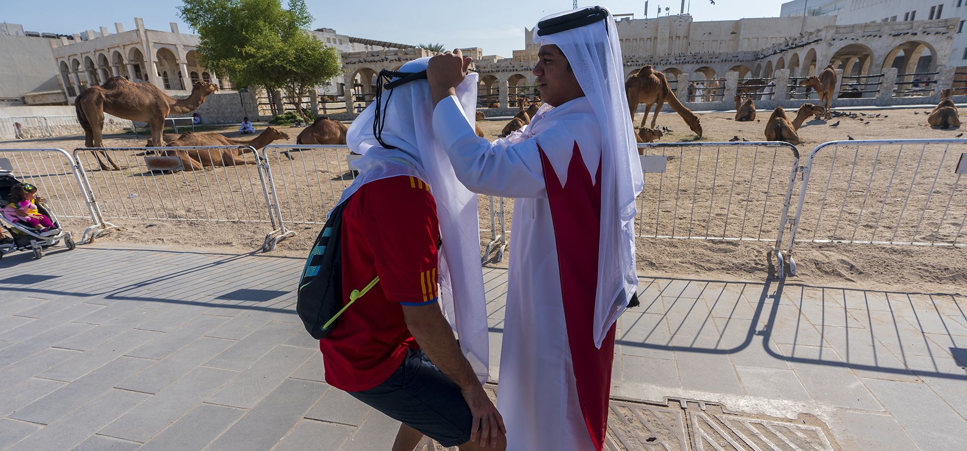 Un hombre ayuda a un turista español a ajustar su tocado tradicional ghutra cerca del mercado Souq Waqif en Doha, Qatar, el jueves 24 de noviembre de 2022. (Foto AP/Moises Castillo)