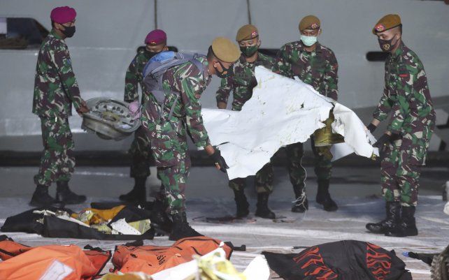 Soldados indonesios llevan piezas de los restos del avión de pasajeros Sriwijaya Air recuperados en el centro de comando de búsqueda y rescate en Yakarta, Indonesia.