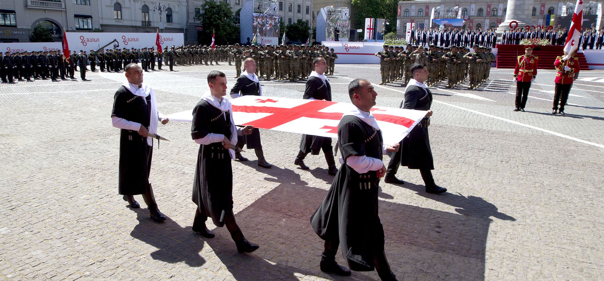Un grupo de hombres llevan la bandera nacional de Georgia durante las celebraciones del Día de la Independencia de Georgia en Tbilisi, Georgia, el jueves 26 de mayo de 2022.