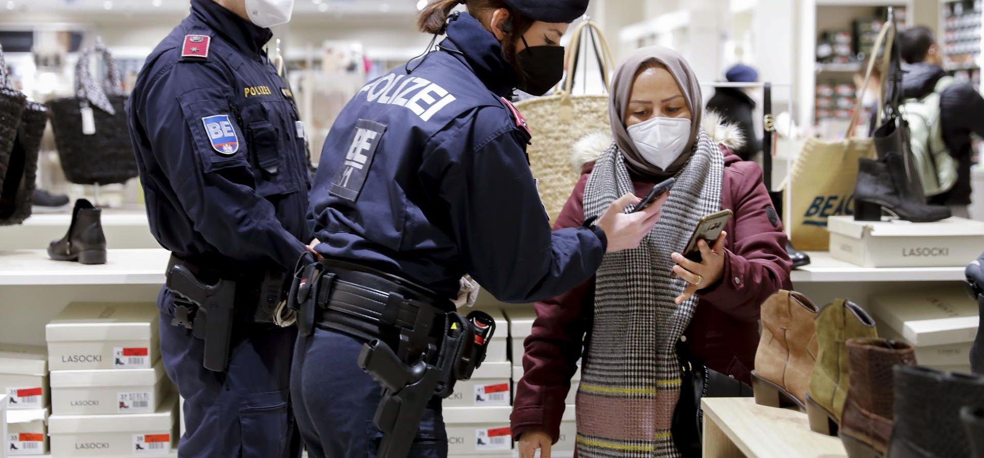 Oficiales de policía verifican el estado de vacunación de un visitante durante un control en un centro comercial en Viena, Austria, el miércoles 12 de enero de 2022.