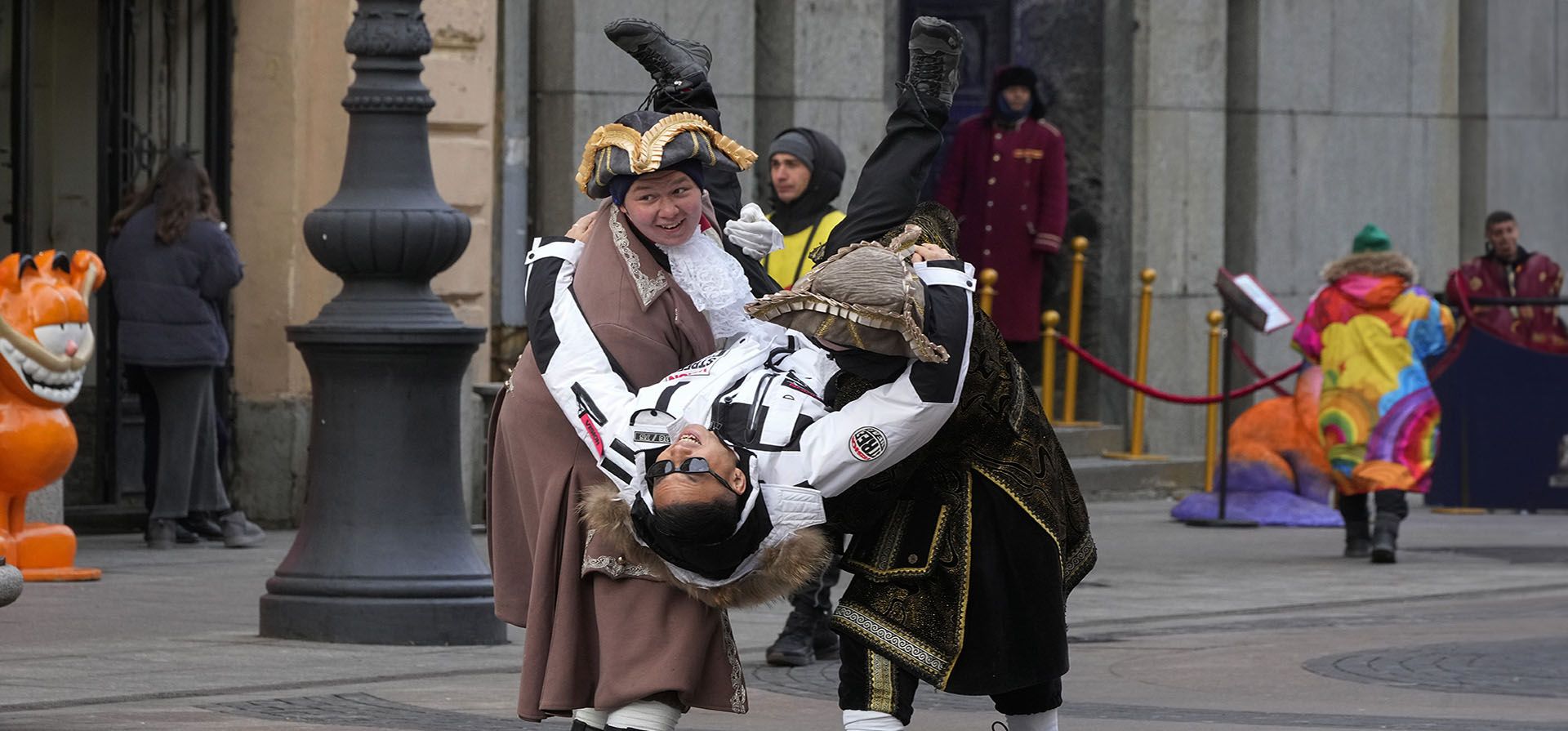 Artistas callejeros que obtiene dinero posando para fotos, ponen boca abajo a un turista chino en San Petersburgo, Rusia, el jueves 21 de noviembre de 2024. (Foto AP/Dmitri Lovetsky)