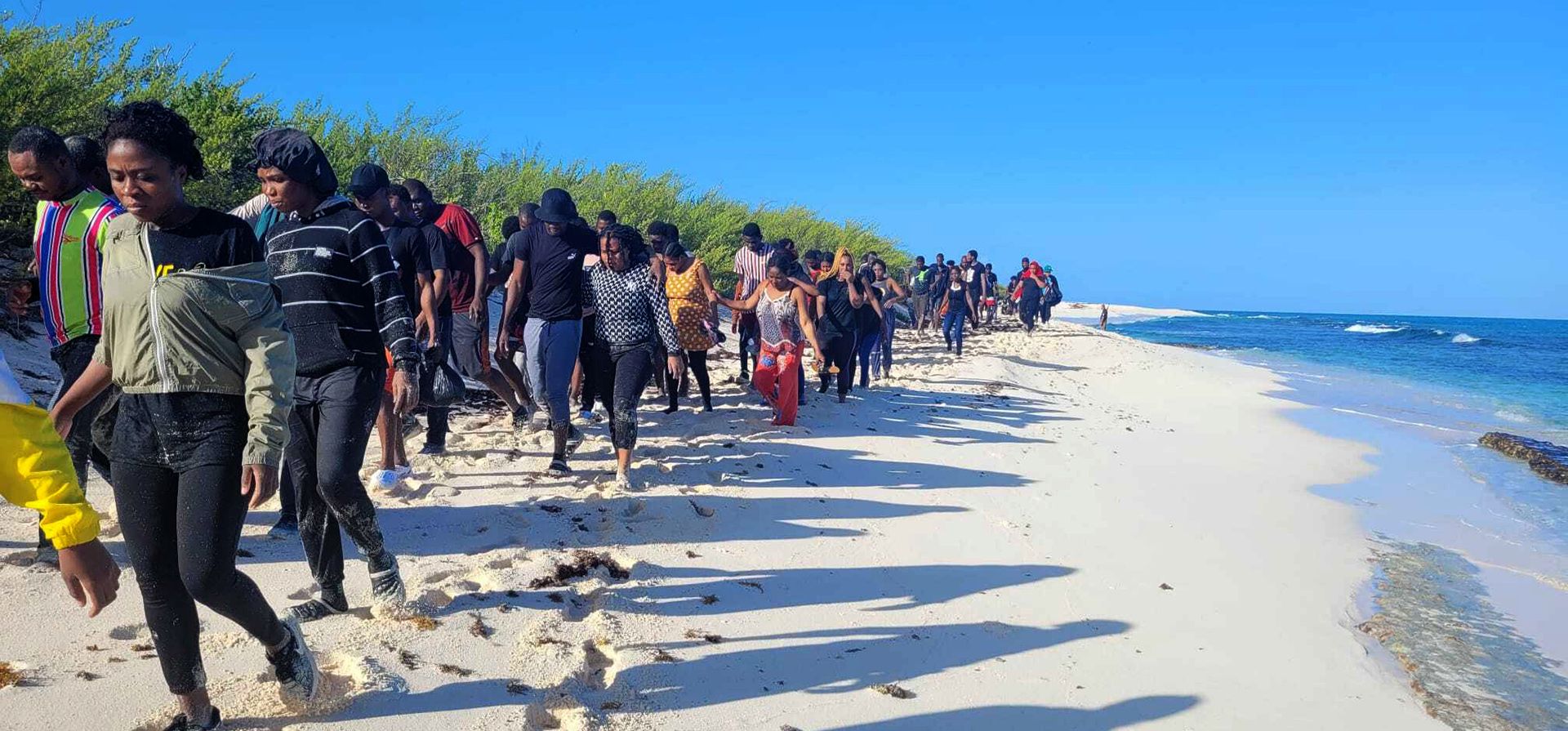 Migrantes rescatados caminan por la costa frente a la isla de Mona, al oeste de Puerto Rico, el jueves 28 de julio de 2022. Al menos cinco migrantes se ahogaron y decenas más fueron rescatados el jueves luego de un presunto contrabando de personas.