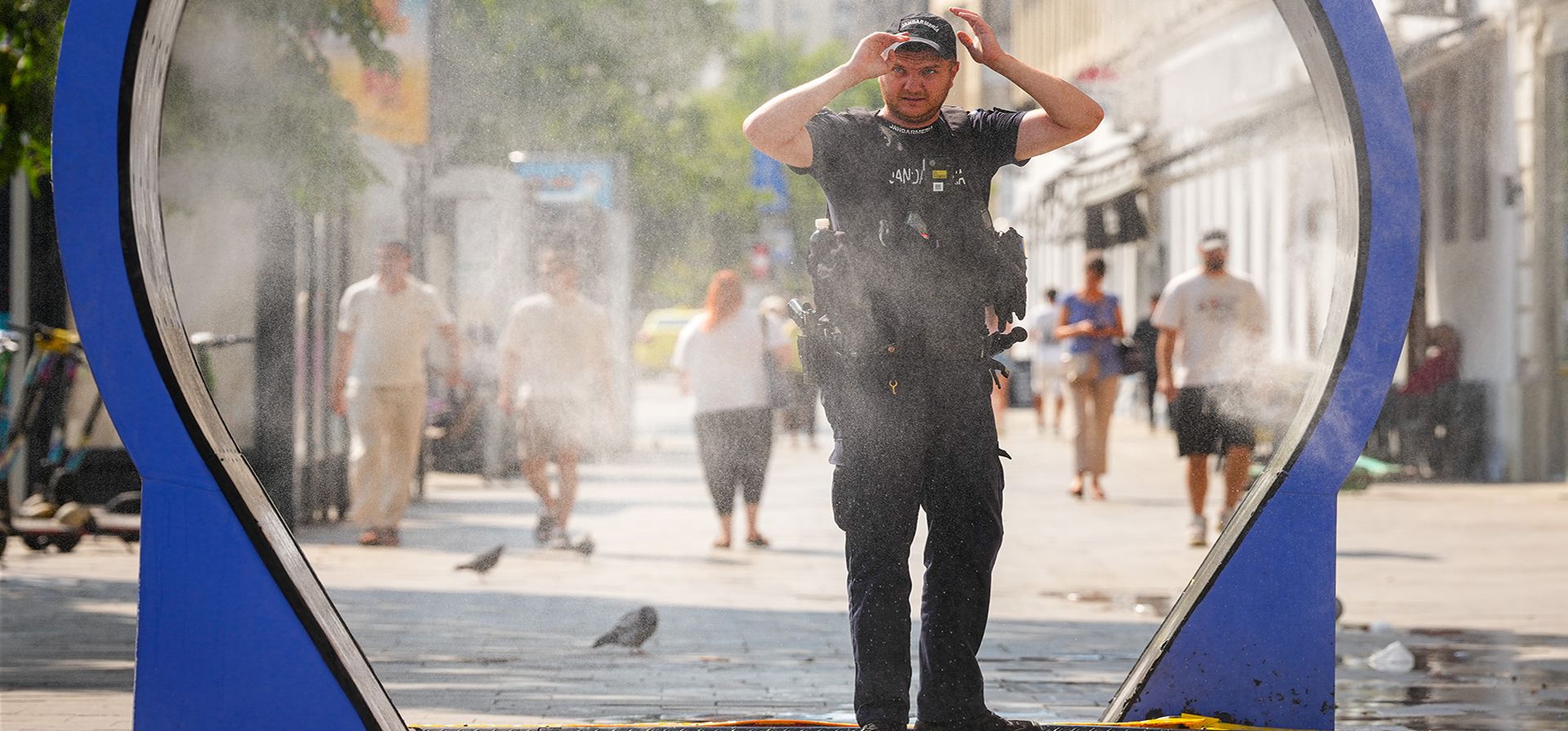 Un gendarme se detiene mientras camina bajo una máquina de nebulización de agua instalada por la administración municipal para ayudar a la población a sobrellevar el calor, en Bucarest, Rumania, el jueves 6 de agosto de 2026. (Foto AP/Vadim Ghirda) Un gendarme se detiene mientras camina bajo una máquina de nebulización de agua instalada por la administración municipal para ayudar a la población a sobrellevar el calor, en Bucarest, Rumania, el jueves 6 de agosto de 2026. (Foto AP/Vadim Ghirda)