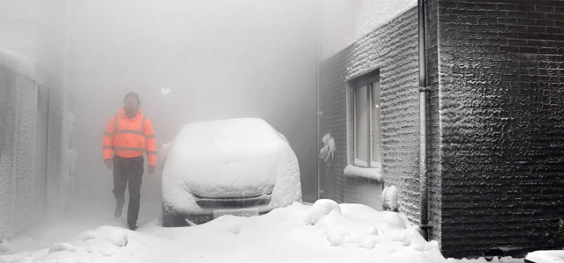 Un ingeniero camina a través de una tormenta de nieve simulada entre dos casas construidas para desarrollar futuras soluciones de calefacción en la Universidad de Salford, Reino Unido. Fotografía: Paul Ellis/AFP/Getty Images