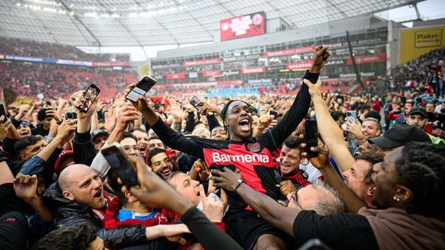 Jeremie Frimpong celebra junto a una multitud de hinchas en el campo de juego el campeonato del Bayer Leverkusen en la Bundesliga.