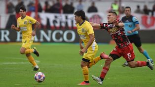 Ignacio Malcorra traslada en el partido ante Barracas Central, en el torneo pasado. El árbitro Lobo Medina observa la acción.
