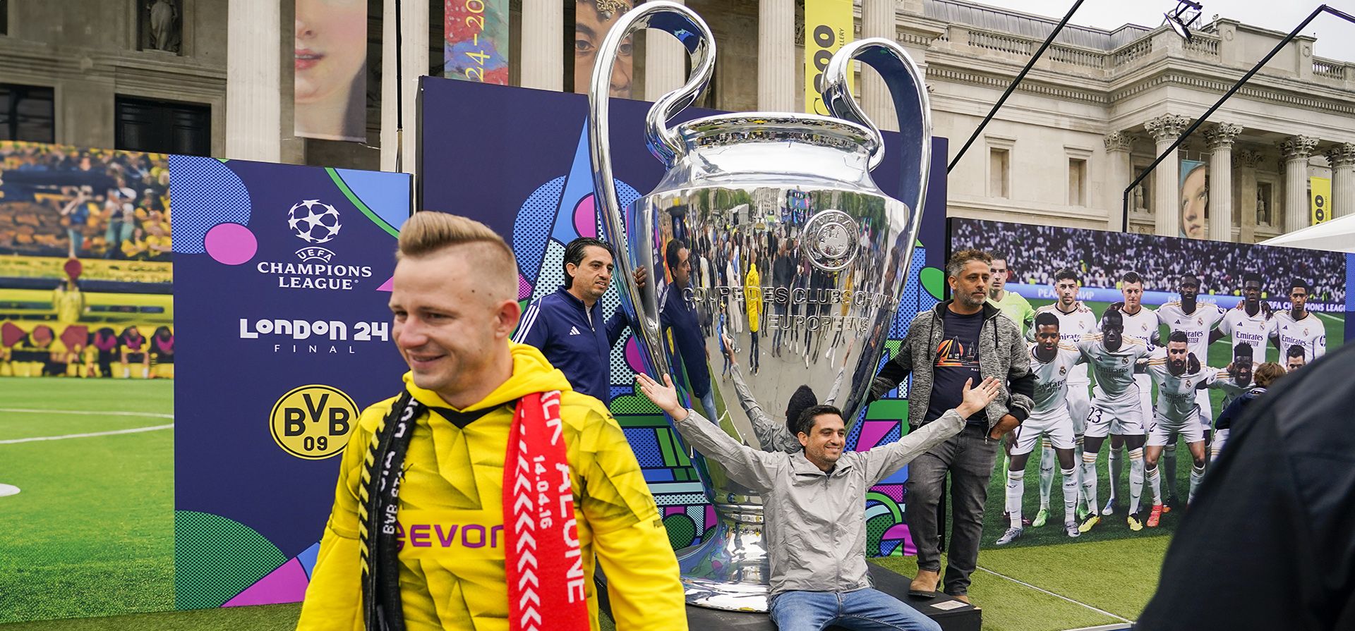 Aficionados posan para fotografías junto a una copia gigante del trofeo en una zona de aficionados en Trafalgar Square, en Londres, el viernes 31 de mayo de 2024, antes de la final de la Liga de Campeones de la UEFA de mañana en el estadio de Wembley entre el Borussia Dortmund y el Real Madrid. (Foto AP/Alberto Pezzali)