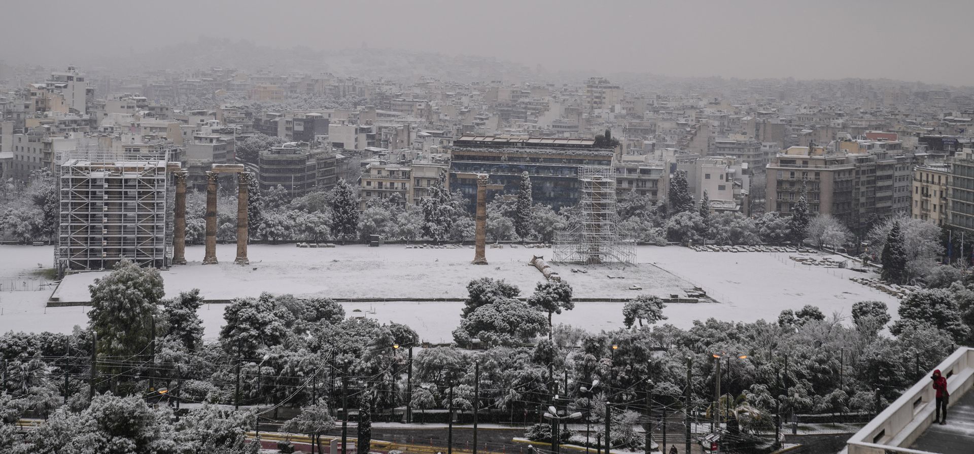 Una mujer observa el antiguo templo de Zeus cubierto de nieve durante una nevada, en Atenas. Las autoridades han advertido al público que evite todos los movimientos al aire libre, excepto los esenciales, y varias carreteras y autopistas principales son transitables solo con cadenas para la nieve.