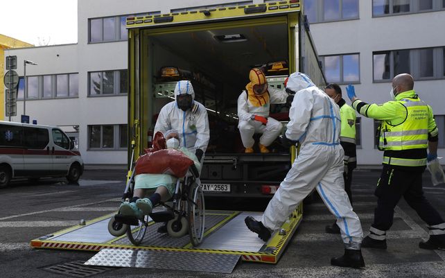Trabajadores de la salud transportan a un paciente con COVID-19