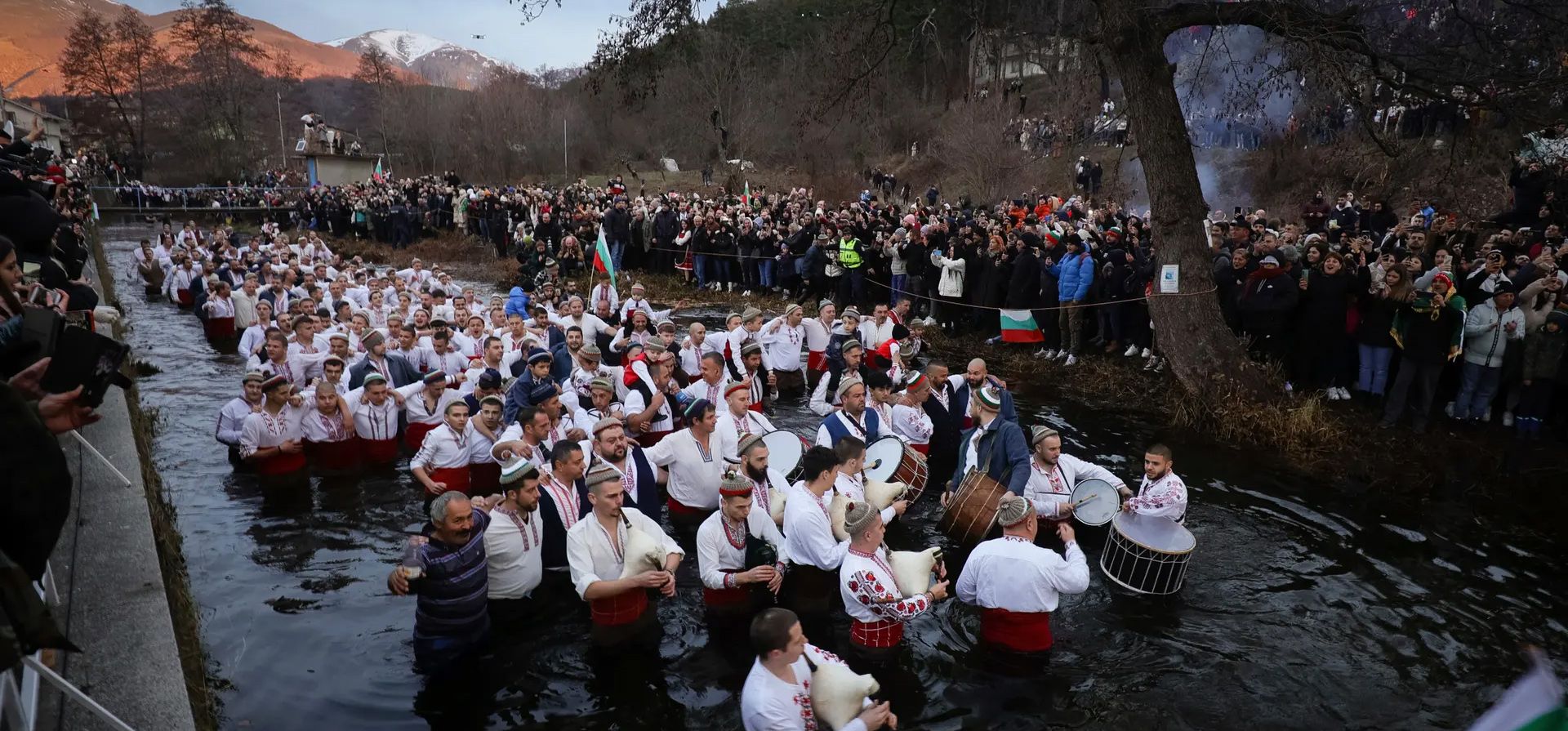 Los hombres tocan gaitas y tambores mientras vadean el río Tundzha para celebrar la Epifanía. La leyenda dice que la persona que recupere una cruz de madera del río se liberará de los malos espíritus y estará sana durante todo el año, Kalofer, Bulgaria. Fotografía: Valentina Petrova/AP Los hombres tocan gaitas y tambores mientras vadean el río Tundzha para celebrar la Epifanía. La leyenda dice que la persona que recupere una cruz de madera del río se liberará de los malos espíritus y estará sana durante todo el año, Kalofer, Bulgaria. Fotografía: Valentina Petrova/AP