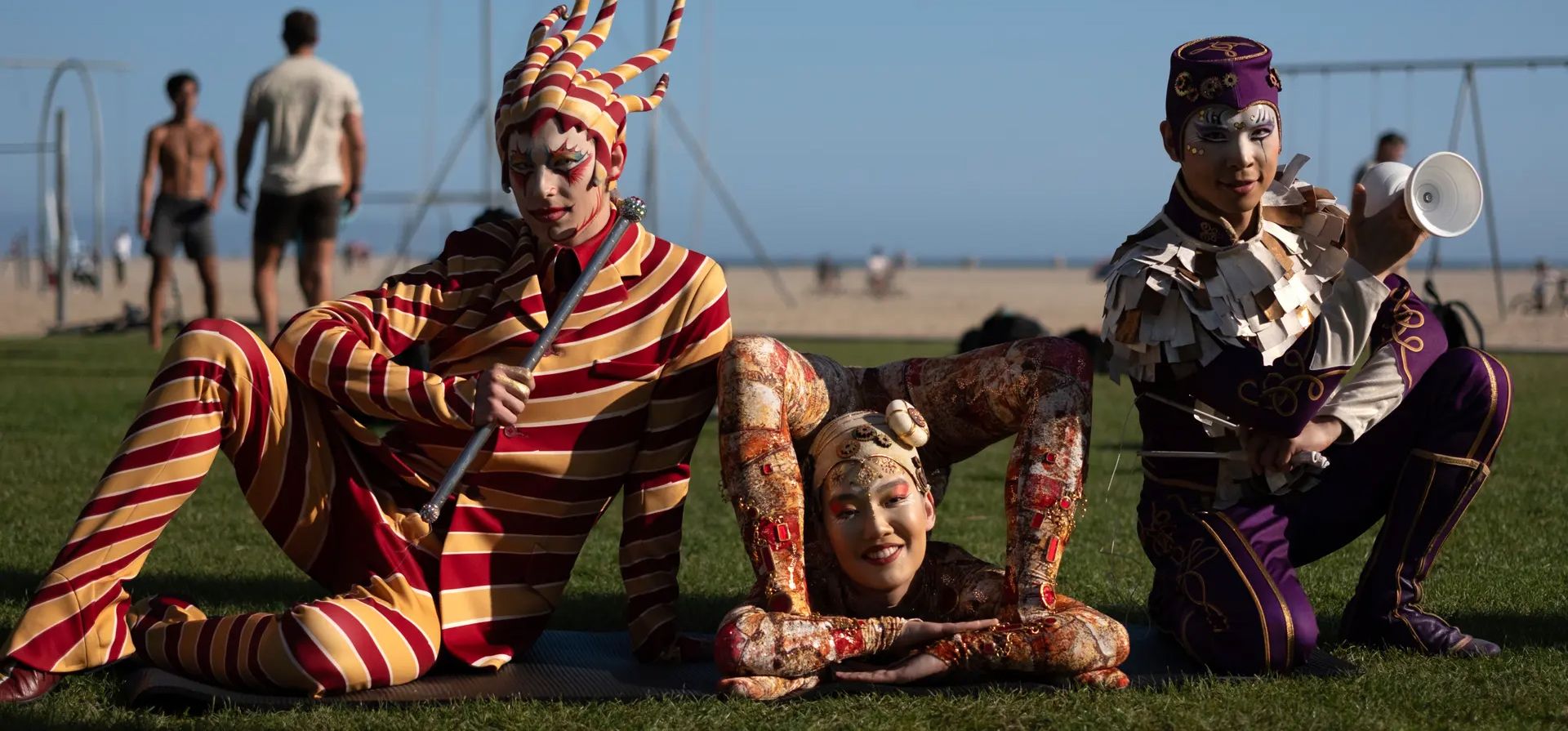 El artista del Cirque du Soleil Mitch Wynter, conocido como el Tramposo, (izquierda) está acompañado por el contorsionista Sender Enkhtur (centro) y el intérprete de diábolo Wei-Liang Lin en la playa de Santa Mónica, Estados Unidos. Fotografía: Richard Vogel/AP El artista del Cirque du Soleil Mitch Wynter, conocido como el Tramposo, (izquierda) está acompañado por el contorsionista Sender Enkhtur (centro) y el intérprete de diábolo Wei-Liang Lin en la playa de Santa Mónica, Estados Unidos. Fotografía: Richard Vogel/AP
