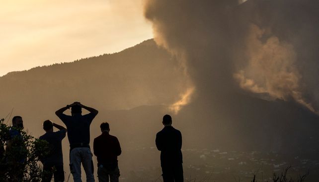 Residentes contemplan como el humo y la lava fluye de una de las colinas del volcán.