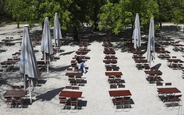 Un empleado prepara los bancos y mesas para la reapertura de la taberna al aire libre Taxisgarten en Munich