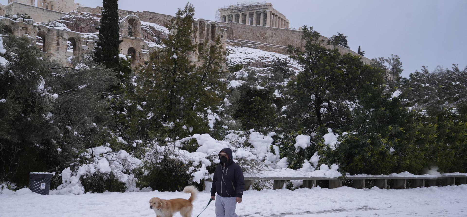 Un peatón camina con su perro sobre la nieve frente a la antigua colina de la Acrópolis, en Atenas. Una tormenta de nieve de gravedad interrumpió el tráfico aéreo y por carretera en la capital griega de Atenas y la vecina Turquía.