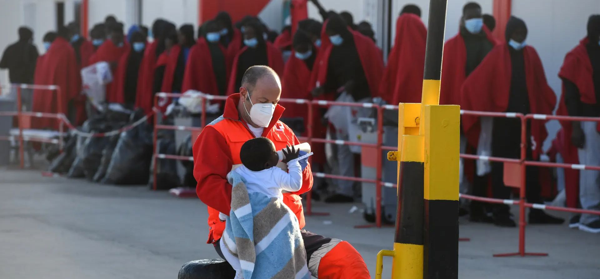 Un miembro de Cruz Roja alimenta a un bebé en el puerto de Gran Carajal tras la llegada de refugiados y migrantes a bordo de un barco de una unidad de salvamento marítimo española, Gran Canaria, Islas Canarias. Fotografía: Carlos de Saá/EPA