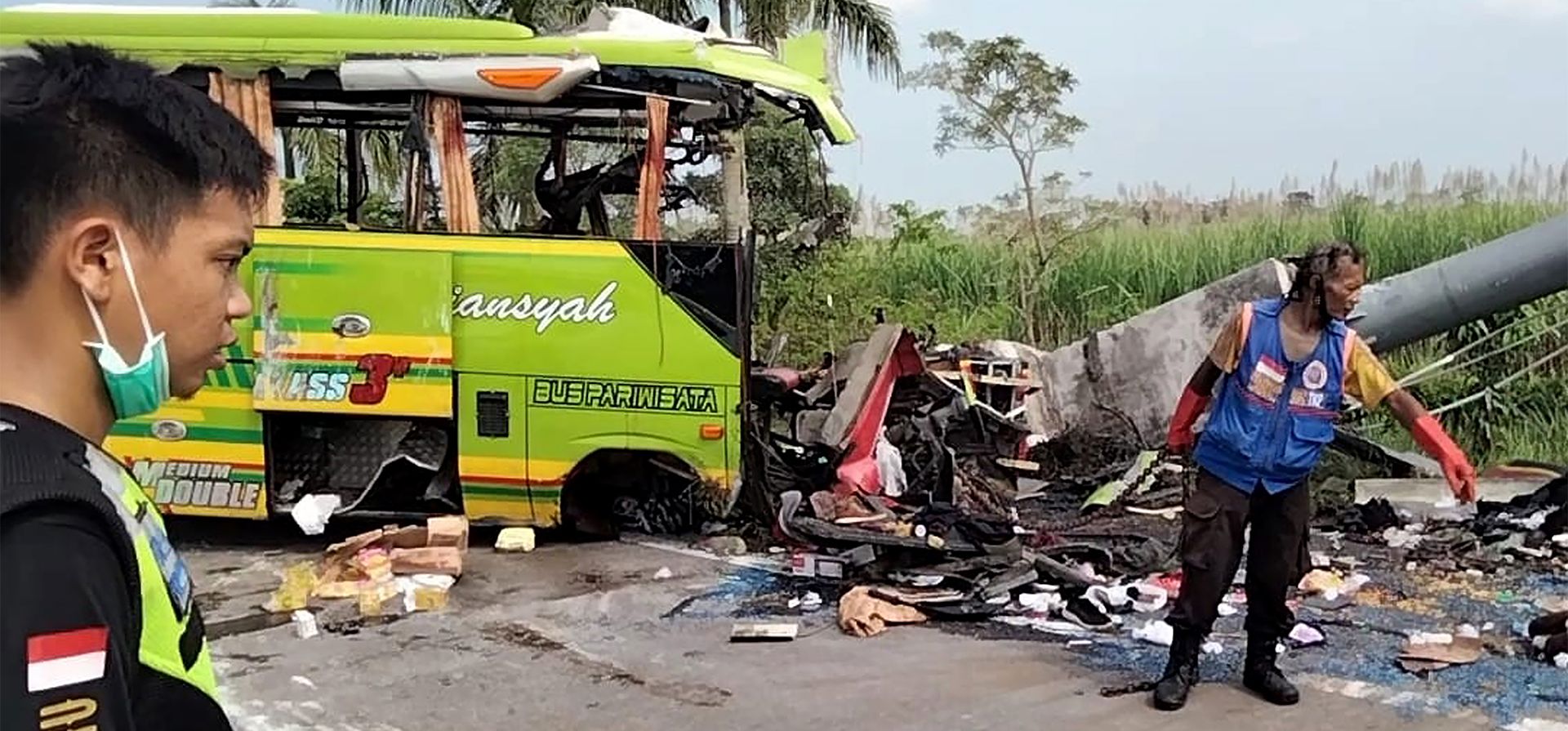 Equipos de rescate inspeccionan los restos de un autobús turístico que se estrelló contra un letrero de una calle en una carretera en Mojokerto, Java Oriental, Indonesia, el lunes 16 de mayo de 2022. El accidente dejó varios muertos e hirió a varias personas.