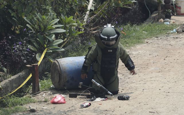 Un miembro del escuadrón de desactivación de bombas de la policía inspecciona un paquete sospechoso encontrado dentro de un contenedor de basura