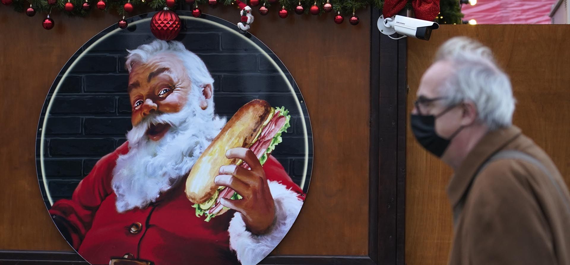 Una mujer que porta un protector facial pasa junto a una imagen de Santa Claus en un mercado navideño, en Londres, el jueves 16 de diciembre de 2021. El Reino Unido registró el miércoles el número más alto de nuevas infecciones confirmadas por COVID-19 desde que comenzó la pandemia. y el director médico de Inglaterra advirtió que es probable que la situación empeore. Foto: AP