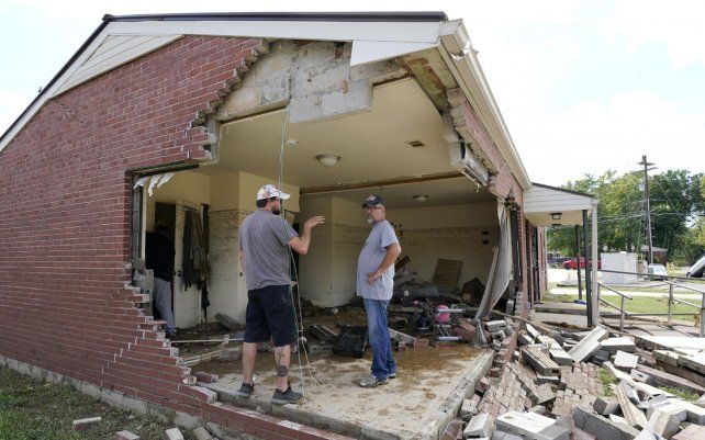 Dos amigos observan una casa casa dañada, en Waverly, Tennessee. Las fuertes lluvias causaron inundaciones en Middle Tennessee y han causado múltiples muertes debido a que las casas y los caminos rurales fueron arrasados.
