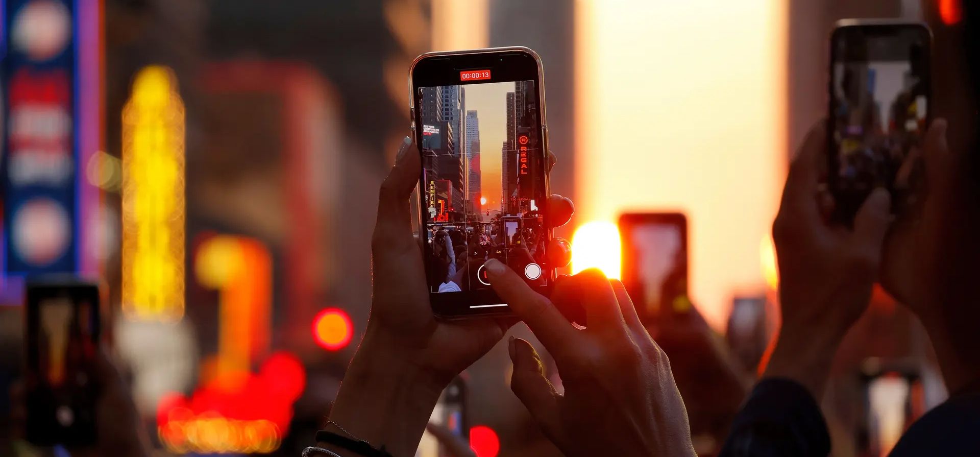 Los teléfonos con cámara se mantienen en alto en la calle 42 mientras la ciudad está bañada por luz dorada. Fotografía: Gary Hershorn/Getty Images