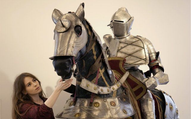 Un empleada de Bonhams mira un conjunto de armadura completa ecuestre de estilo alemán de finales del siglo XVI para un hombre y un caballo, durante una sesión fotográfica para la venta de armas y armaduras antiguas de la empresa de subastas británica en Londres.