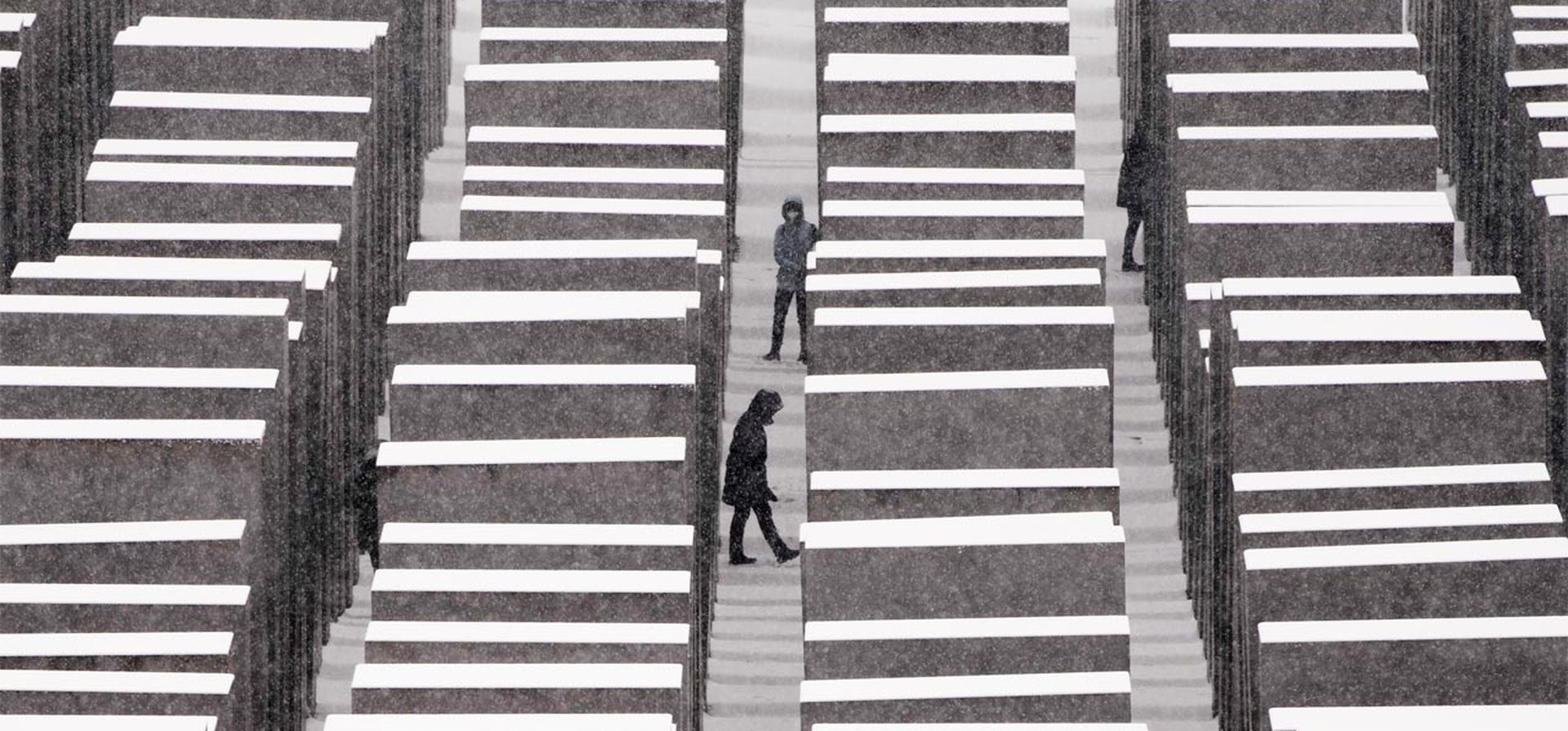 La gente visita el Monumento a los Judíos Asesinados de Europa, el llamado Monumento al Holocausto durante la caída de nieve en Berlín, Alemania, el jueves 9 de diciembre de 2021.