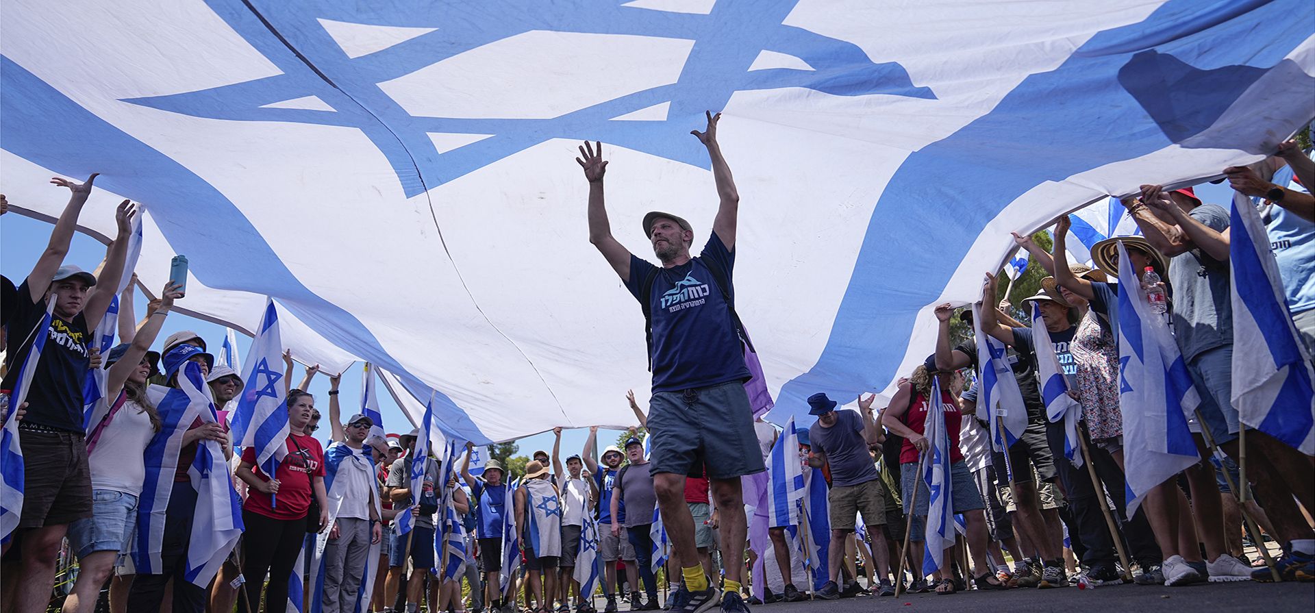 Manifestantes ondean una gran bandera israelí durante una protesta contra los planes del gobierno del primer ministro Benjamin Netanyahu para reformar el sistema judicial, frente a la Knesset, el parlamento de Israel, en Jerusalén, el lunes 24 de julio de 2023. (Foto AP/Ohad Zwigenberg) Manifestantes ondean una gran bandera israelí durante una protesta contra los planes del gobierno del primer ministro Benjamin Netanyahu para reformar el sistema judicial, frente a la Knesset, el parlamento de Israel, en Jerusalén, el lunes 24 de julio de 2023. (Foto AP/Ohad Zwigenberg)