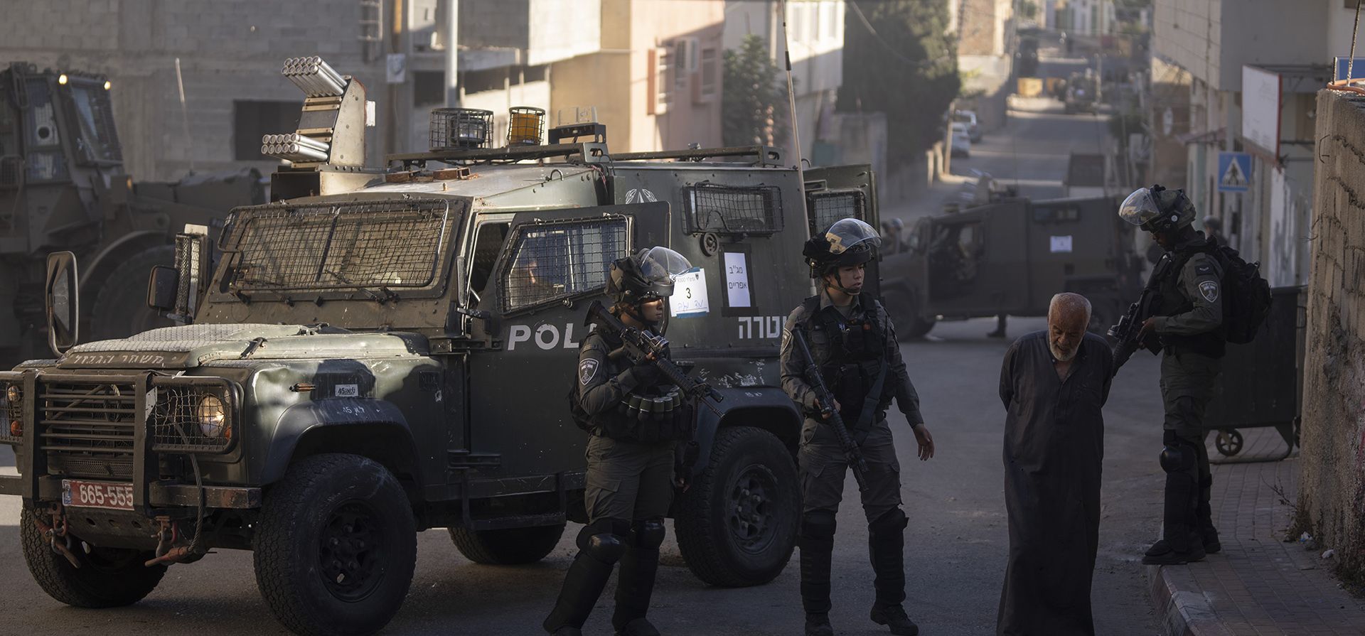 Un anciano palestino es enviado de regreso por la policía fronteriza israelí, que asegura el perímetro mientras las fuerzas del ejército demuelen la casa familiar del palestino Yahia Merai en la ciudad de Qarawat Bani Hassan, Salfit, en Cisjordania, el martes 26 de julio de 2022.