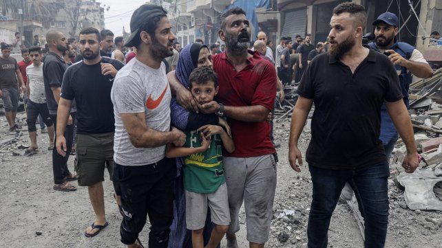 Miembros de una familia palestina consuelan a un niño conmocionado mientras abandonan su casa destruida tras los ataques aéreos israelíes sobre la ciudad de Gaza el 9 de octubre de 2023.&nbsp; &nbsp;
