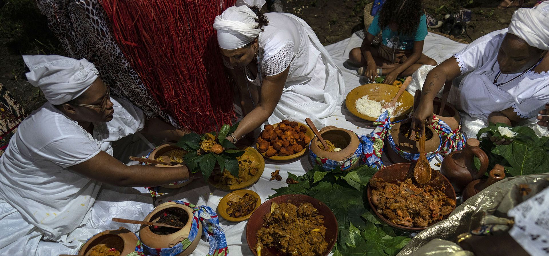Mujeres que practican candomblé sirven platos afrobrasileños en vasijas de barro durante un ritual en honor a la deidad Obaluae, en un templo en las afueras de Salvador, Brasil. Luego de una bendición yoruba dirigida por la matriarca del templo, se sirvió comida en tazones improvisados hechos de hojas.