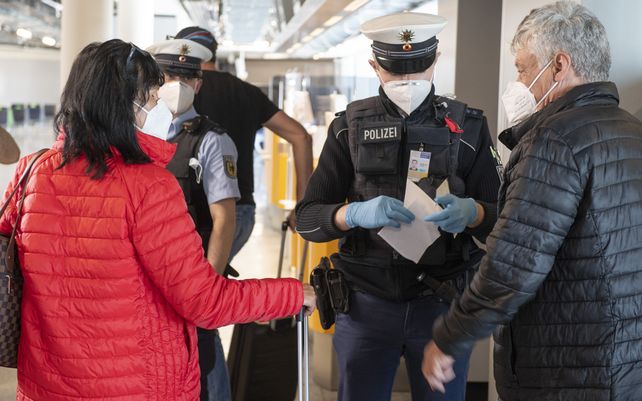 Un policía de migraciones revisa los documentos de los pasajeros que regresan a Alemania en un vuelo desde Palma de Mallorca