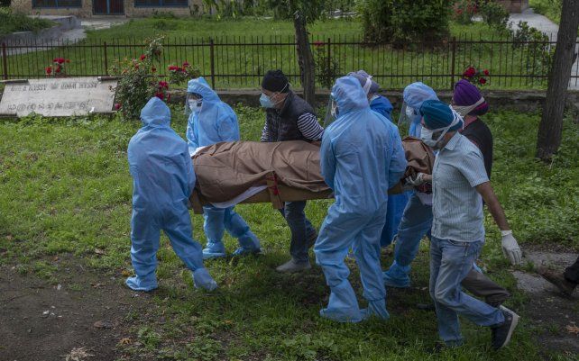 Representantes y voluntarios llevan el cuerpo de una persona que murió de COVID-19, en un crematorio en Srinagar, Cachemira controlada por India.