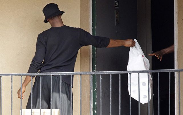 Dallas. Un hombre pasa una bolsa de la Cruz Roja y del Banco de Alimentos en el apartamento donde vive el enfermo.