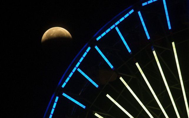 El avance del eclipse lunar se ve detrás de una noria sobre la playa de Santa Mónica en California. El primer eclipse lunar total en más de dos años coincide con una superluna de un gran espectáculo cósmico.