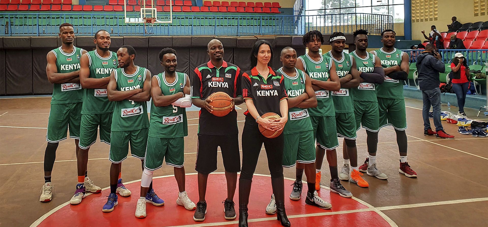 La entrenadora de baloncesto Liz Mills, de la selección nacional de Kenia, posa con el entrenador asistente Sadat Gaya, en el centro a la izquierda, y los jugadores del equipo, en el Estadio Nyayo en Nairobi, Kenia, el sábado 13 de febrero de 2021. La entrenadora de baloncesto Liz Mills ha vuelto a demostrar que las mujeres pueden entrenar con éxito a equipos masculinos.