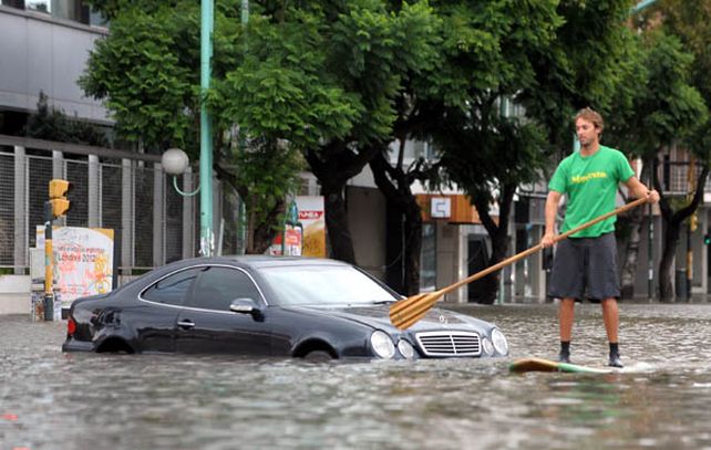 Un vecino de barrio River rema por las calle inundadas.