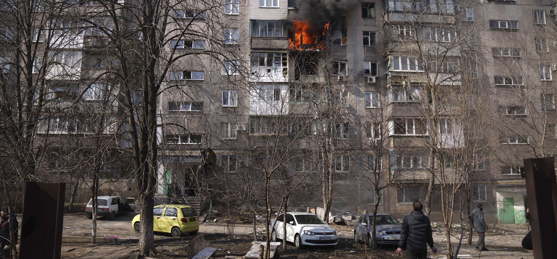 Un residente mira un edificio de apartamentos en llamas después de los bombardeos en Mariupol, Ucrania, el domingo 13 de marzo de 2022.