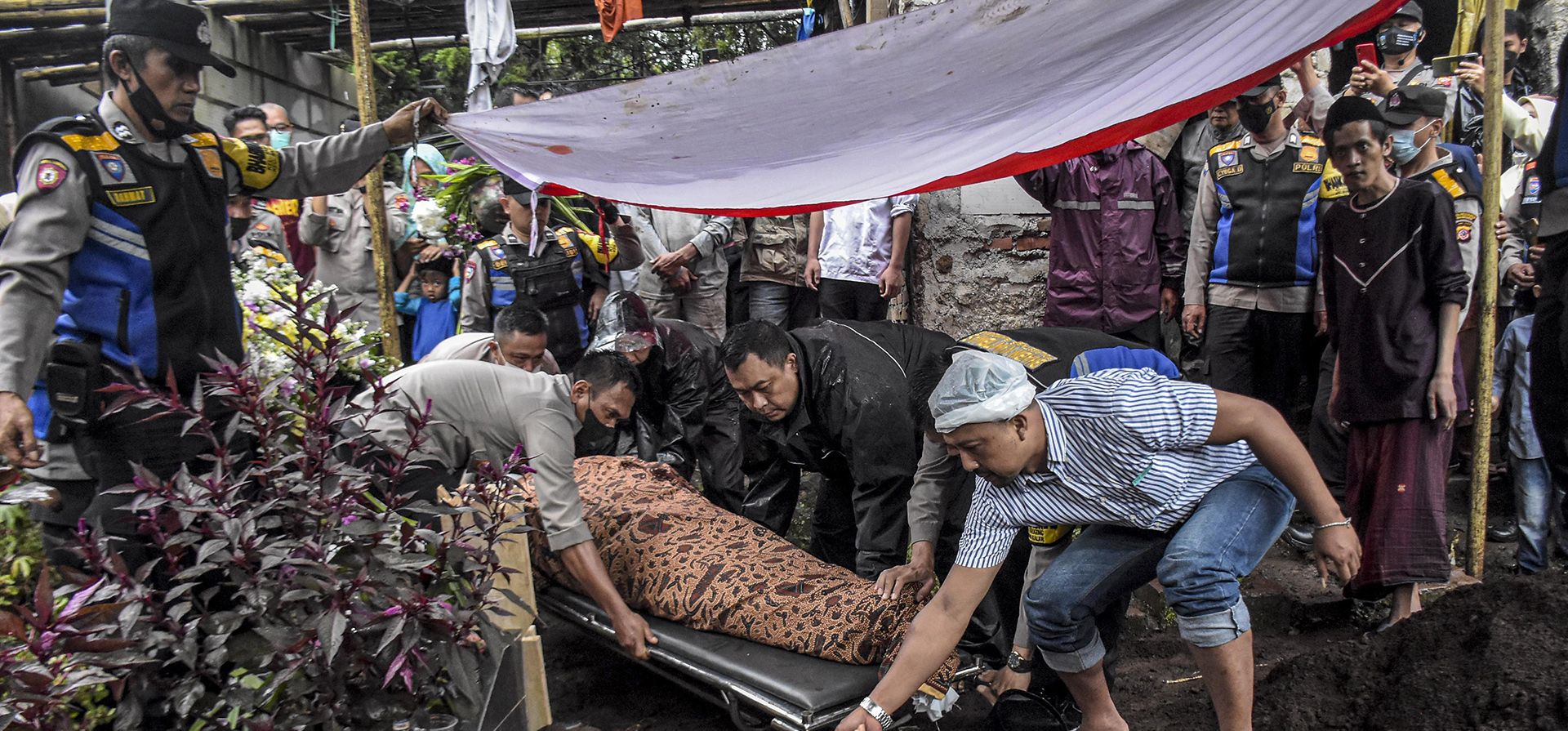 Familiares bajan el cuerpo del segundo subinspector Sofyan, un oficial asesinado después de que una bomba suicida estalló en una estación de policía, a una tumba durante su funeral en Bandung, Java Occidental, Indonesia, el miércoles 7 de diciembre de 2022. (AP Photo/Ahmad Fauzan)