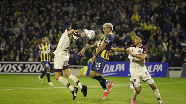 El nuevo centrodelantero de Central Enzo Copetti se esfuerza entre la marca de los jugadores de Lanús Ezequiel Muñoz y el excanalla Nery Domínguez.
