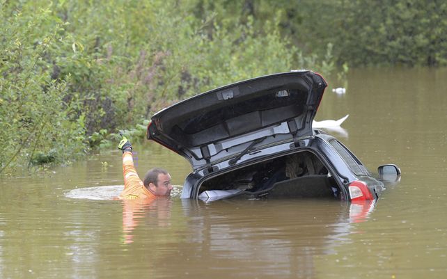 Personal de rescate revisa un automóvil sumergido en una carretera inundada en Falun