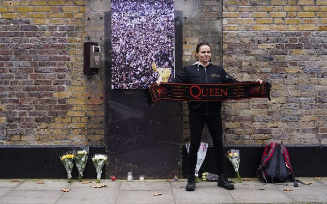 Una fan sostiene una bufanda de la banda de rock británica Queen, mientras posa frente a la casa del difunto Freddie Mercury, en el 30° aniversario de su muerte, en Londres, el miércoles 24 de noviembre de 2021.
