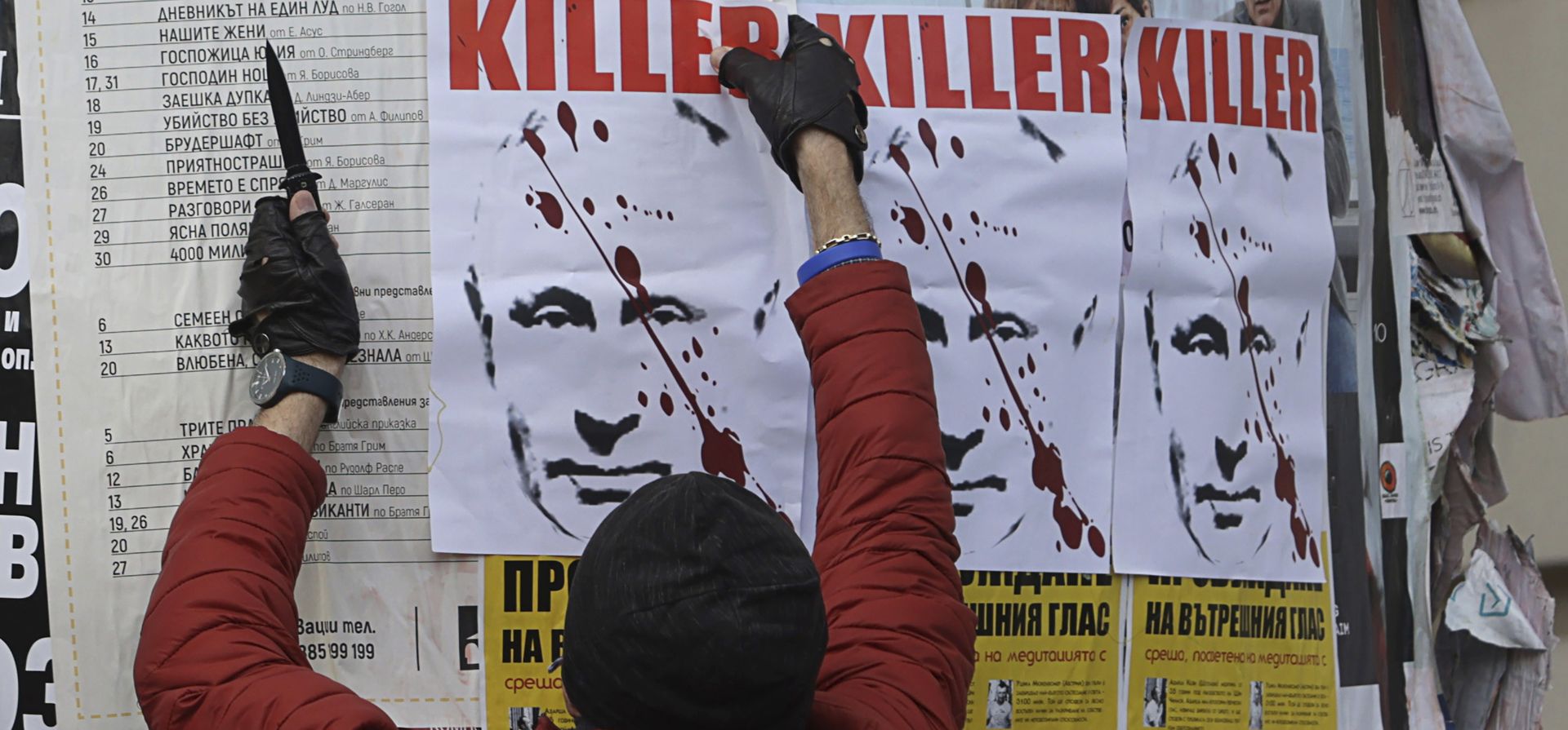 Un hombre intenta quitar un cartel que representa al presidente ruso Vladimir Putin con un letrero que dice