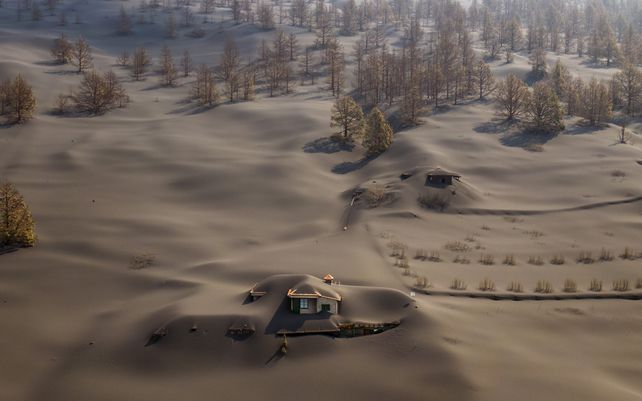 La figura de dos casas cubiertas por la ceniza del volcán en erupción en la isla canaria de La Palma