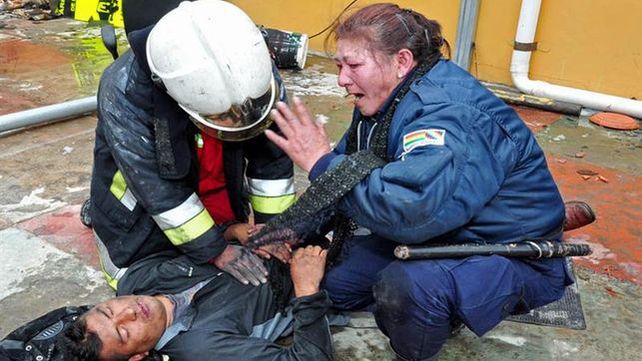 Barbarie. Una oficial no puede contener el llanto mientras un rescatista asiste a una persona con principio de asfixia.