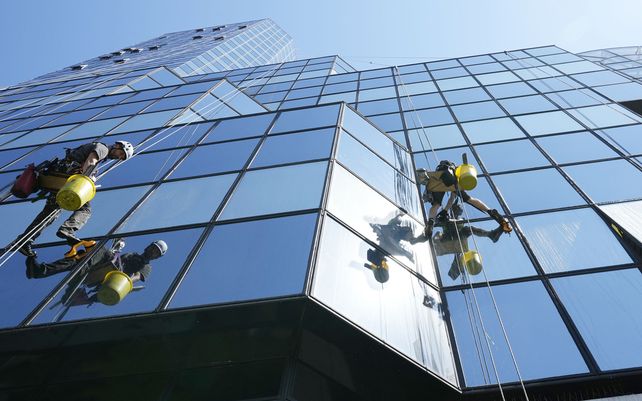 Limpiadores con arnés de seguridad limpian los cristales de un rascacielos en el centro de Varsovia