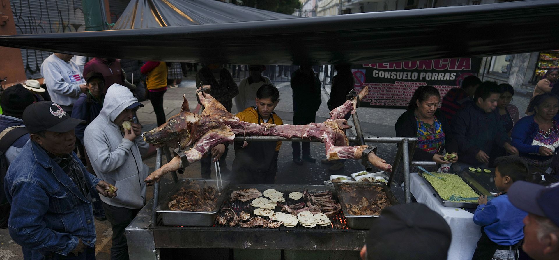 Manifestantes consumen un cerdo asado delante de la policía, en las inmediaciones del Congreso, en la Ciudad de Guatemala, el 28 de noviembre de 2023. Desde hace semanas, los manifestantes reclaman en las calles la renuncia de la fiscal general, Consuelo Porras, luego de que su oficina intervino en el proceso electoral en varias ocasiones. (AP Foto/Moisés Castillo) Manifestantes consumen un cerdo asado delante de la policía, en las inmediaciones del Congreso, en la Ciudad de Guatemala, el 28 de noviembre de 2023. Desde hace semanas, los manifestantes reclaman en las calles la renuncia de la fiscal general, Consuelo Porras, luego de que su oficina intervino en el proceso electoral en varias ocasiones. (AP Foto/Moisés Castillo)
