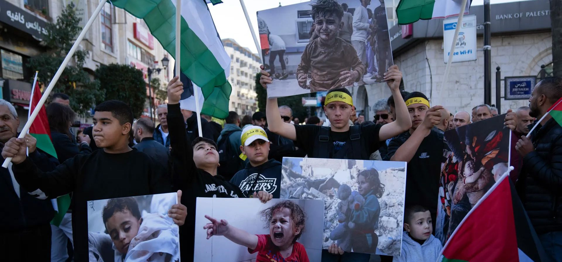 Manifestantes llevan carteles con fotos de palestinos muertos durante el conflicto en Gaza y ondean banderas palestinas durante una manifestación en solidaridad, Ramallah, Cisjordania. Fotografía: Nasser Nasser/AP