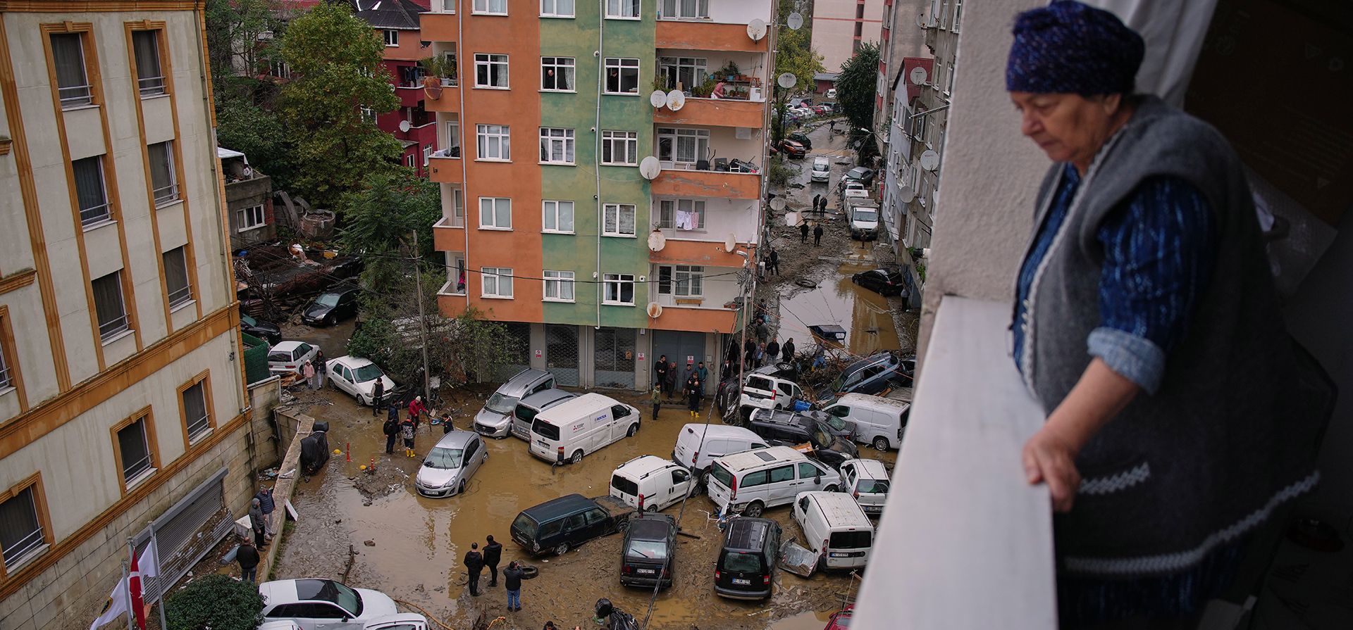 Una mujer contempla desde el balcon de su casa los vehículos volcados y escombros esparcidos tras las inundaciones causadas por fuertes lluvias, en Estambul, Turquía, el jueves 15 de octubre de 2026. (Foto AP/Emrah Gurel)