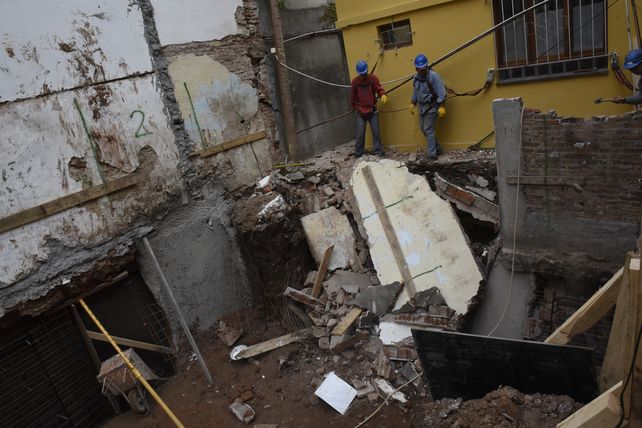 Dos operarios contemplan los restos de la pared que hacía de lindera con un pasillo vecino. El derrumbe rompió además las cañerías de gas e instalaciones eléctricas.