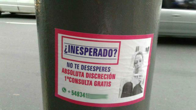 Sobre una columna de alumbrado. El cartel tiene la imagen de una mujer observando el resultado de un test de embarazo.